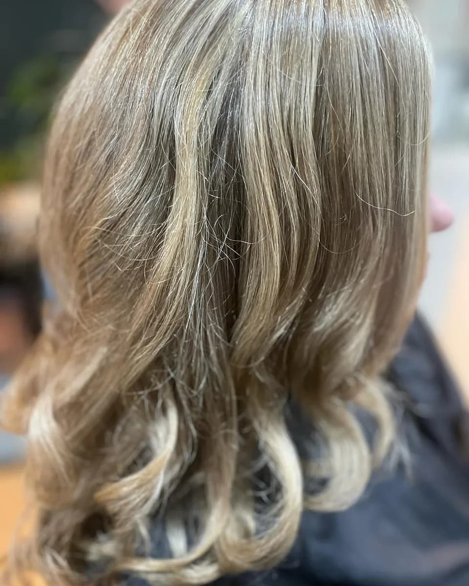 Blonde balayage curled and dressed out, soft through the lengths